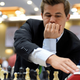 Magnus Carlsen in front of chess board hitting a chess clock.